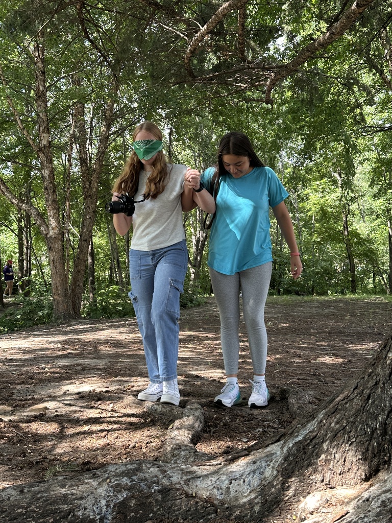 students guiding a blindfolded classmate around so they can take photographs outside