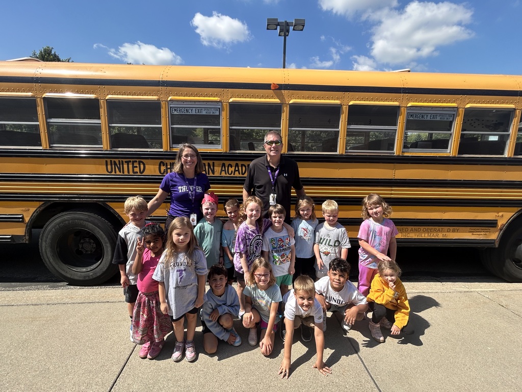 kindergarten class standing beside a school bus