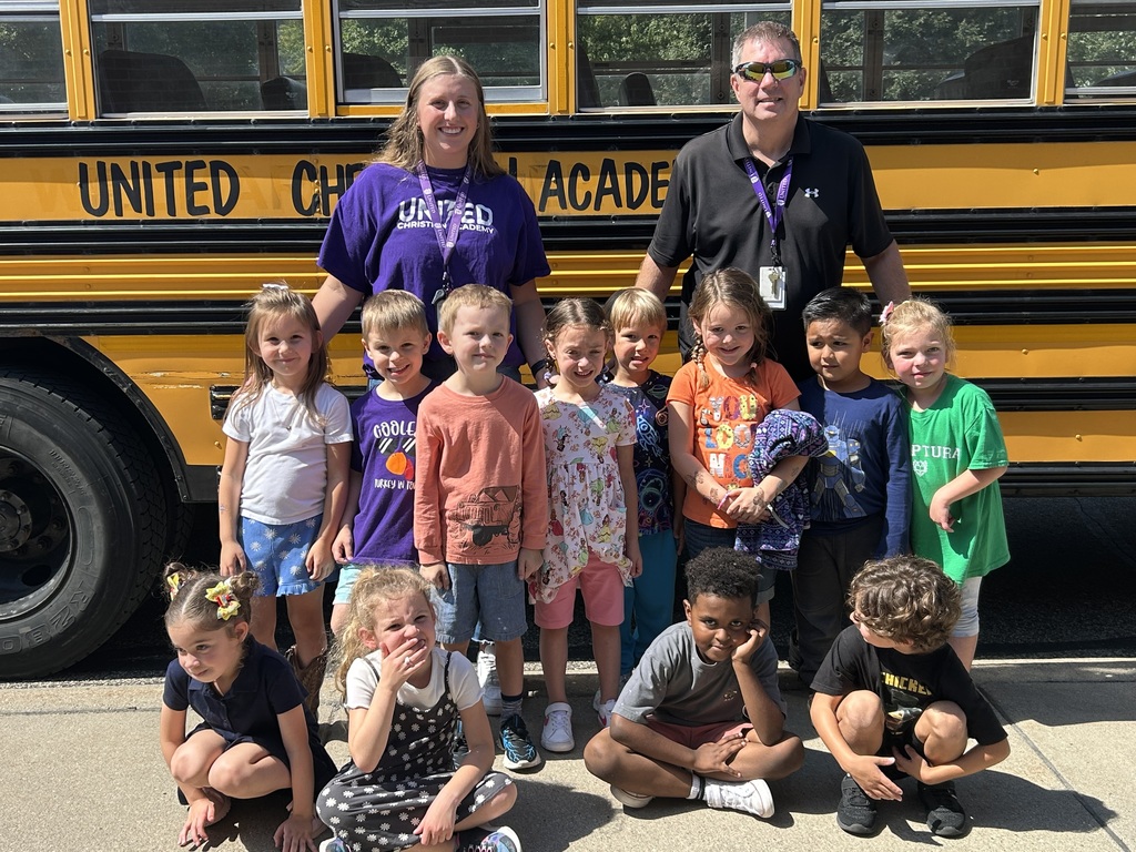 kindergarten class standing beside a school bus
