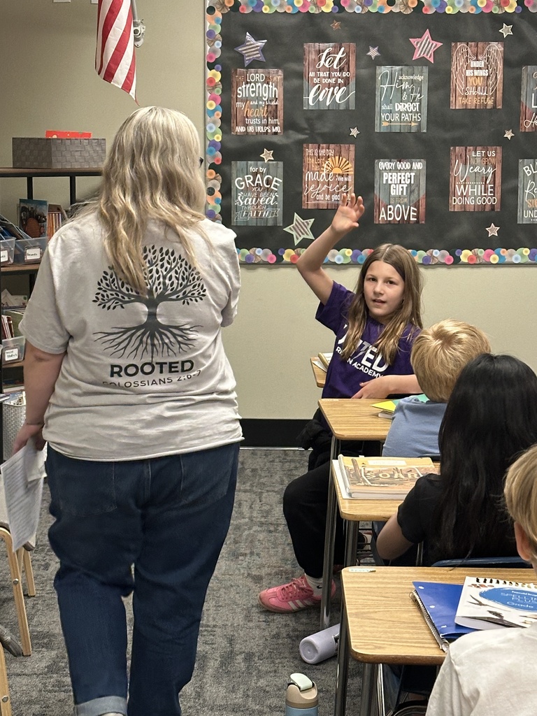 student raising her hand as teacher walks by