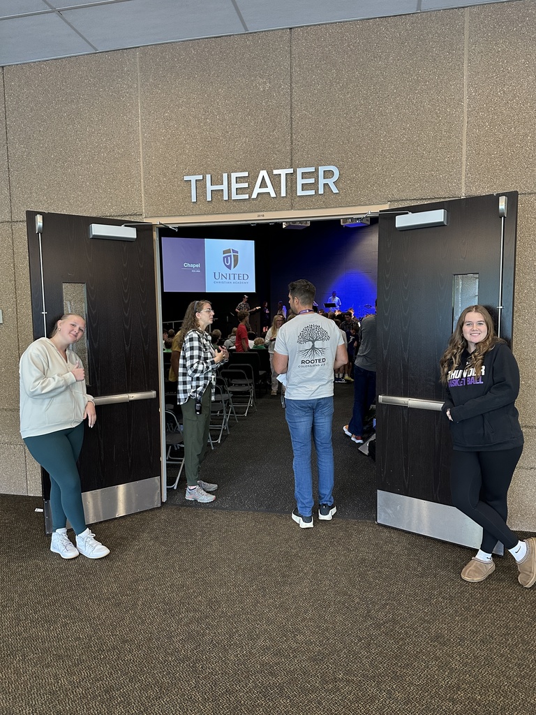 two high school students greeting peers as they walk into chapel
