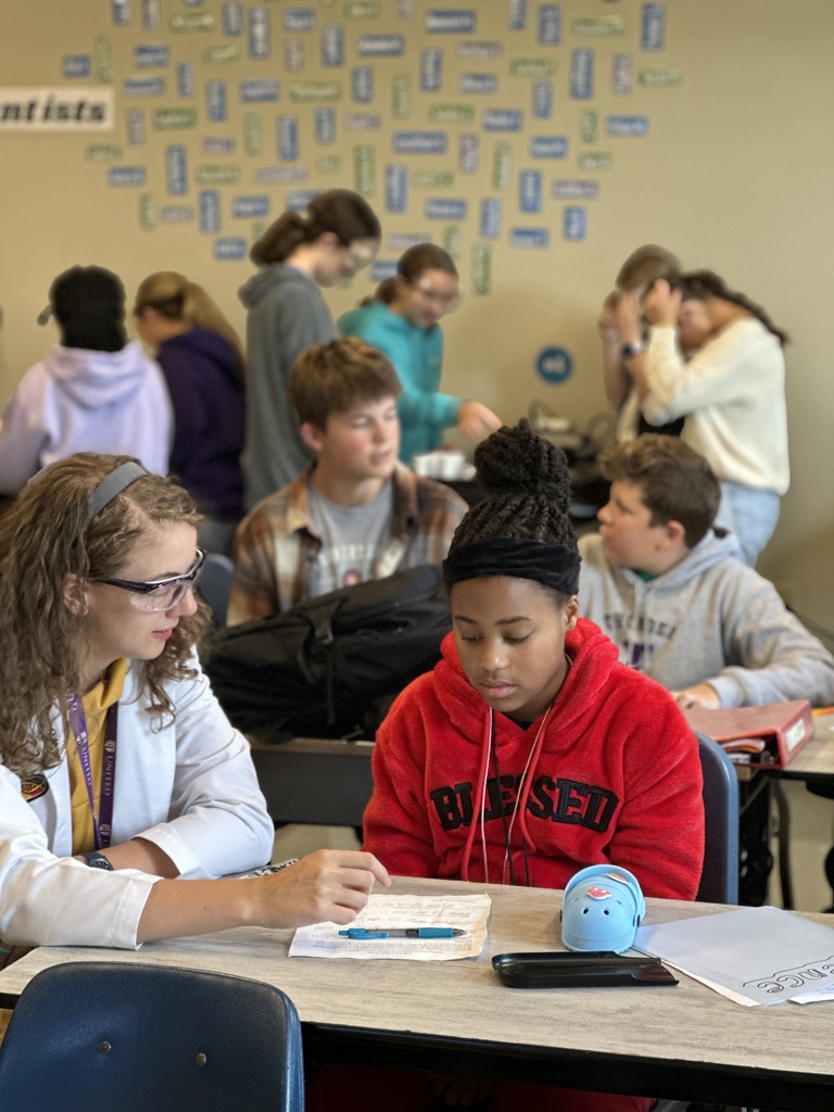 science teacher sitting with her students helping them with their work