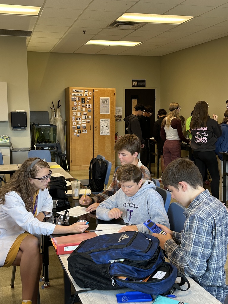 science teacher sitting with her students helping them with their work