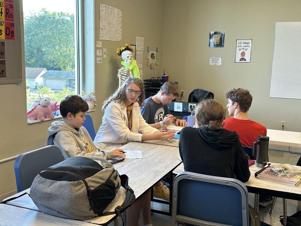 science teacher sitting with her students helping them with their work