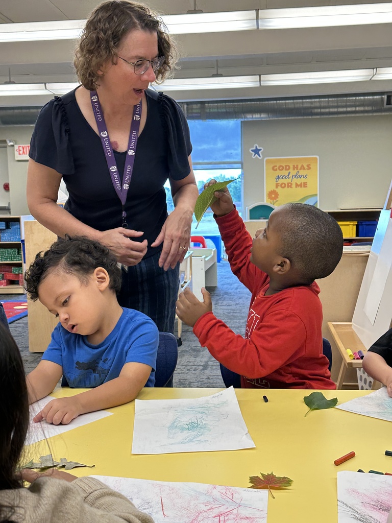 pre-k student showing his teacher a leaf
