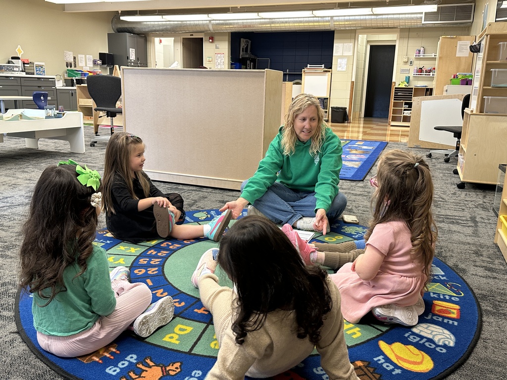 pre-K students sitting on the rug with their teacher
