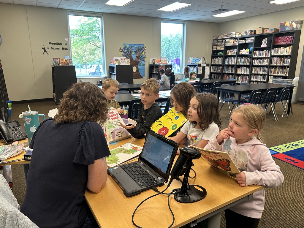 kindergarten students checking out books from the library