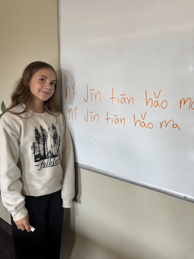 high school student standing by the white board writing Chinese characters
