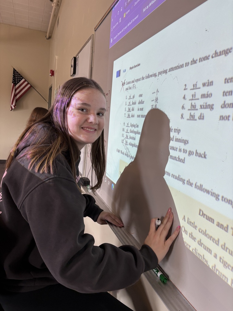high school student standing by the white board writing Chinese characters