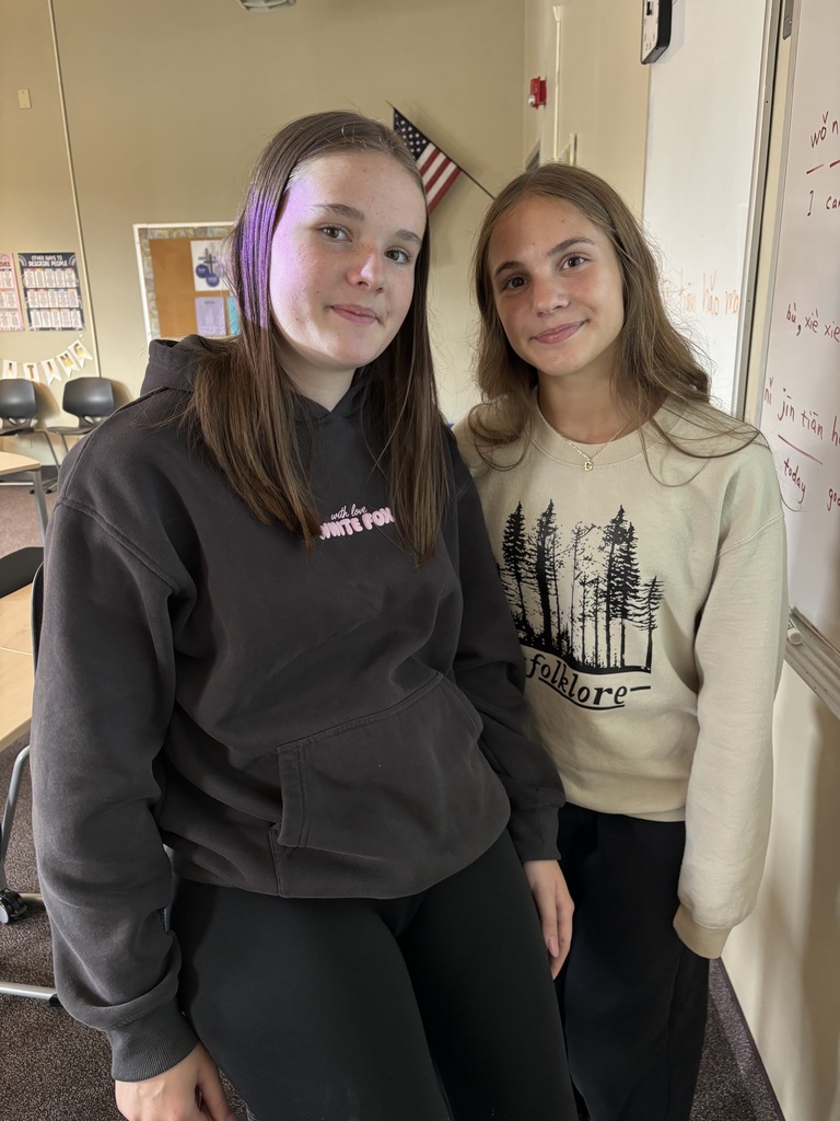 two high school girls in Chinese class standing by the white board