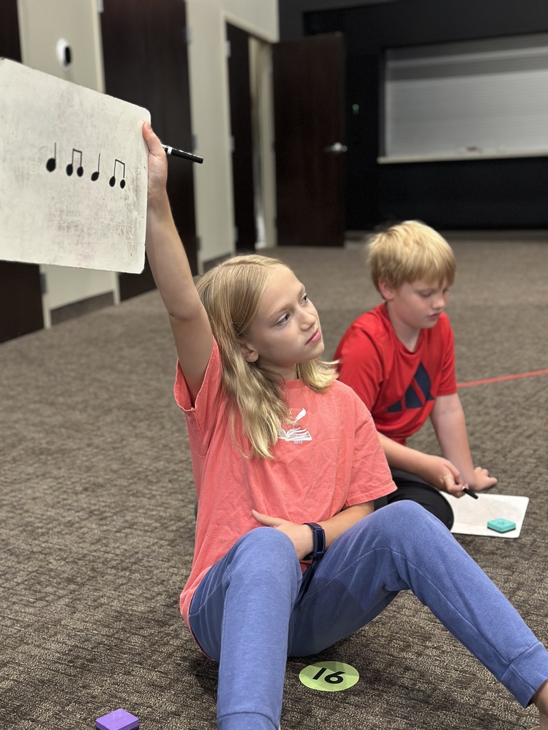 5th grade student showing the teacher the music notes she drew on a whiteboard