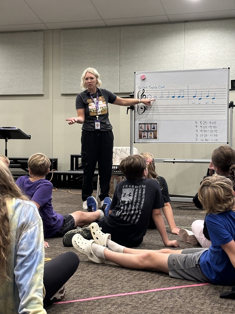 Music teacher at a whiteboard teaching students about the treble clef