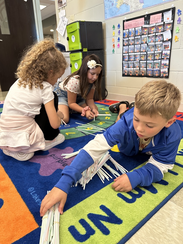 students sitting on the floor counting bundles of straws