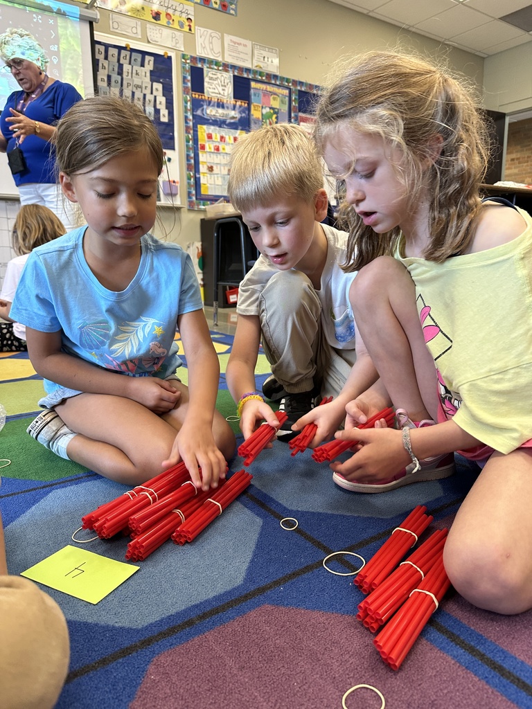 students sitting on the floor counting bundles of straws