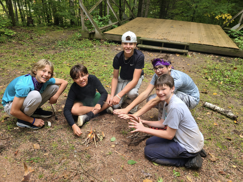 group of 7th and 8th grade boys starting a campfire
