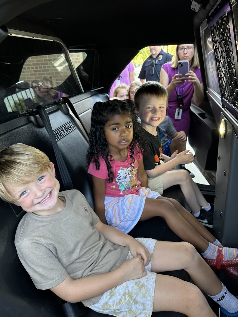 kindergarten students sitting inside of a squad car