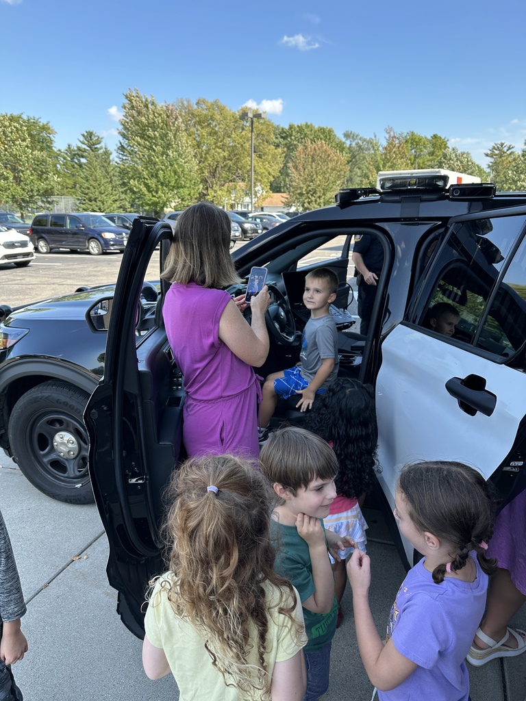 kindergarten teacher taking pictures of students sitting in a squad car