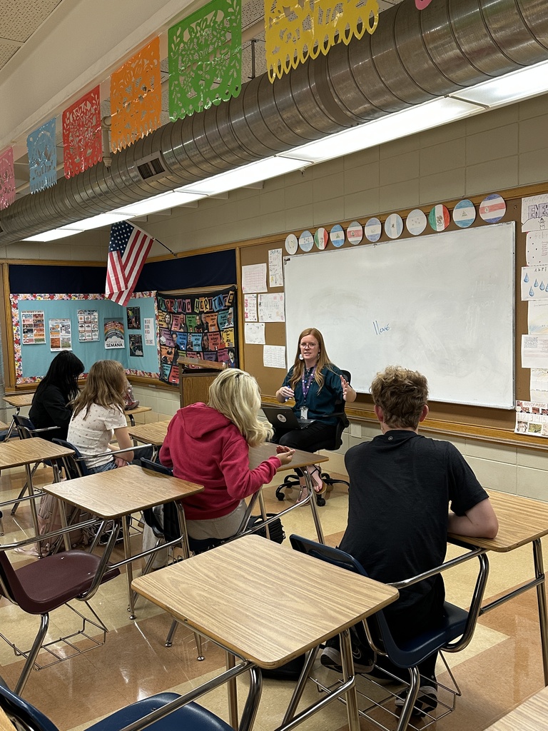 teacher speaking in the front of a classroom to her students