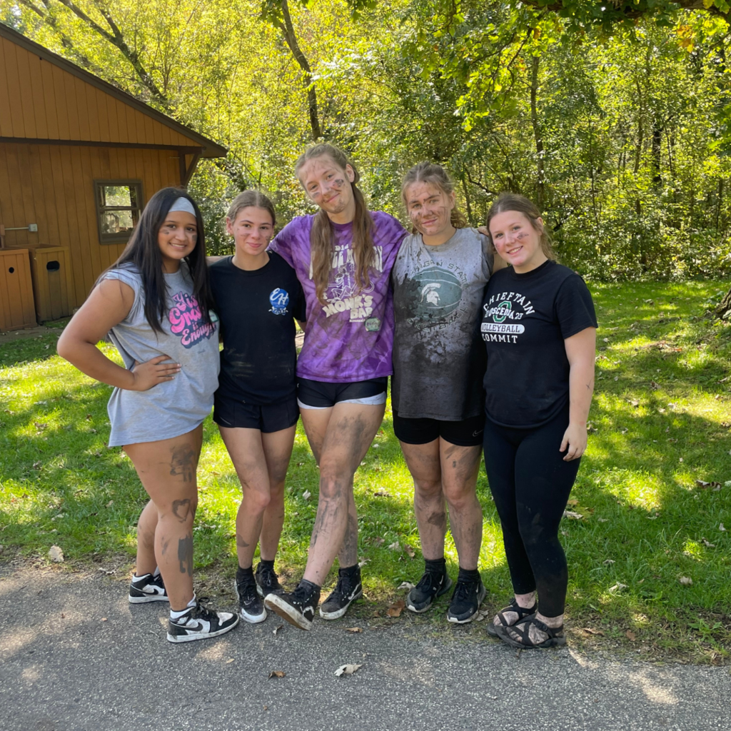 group of high school girls showing how muddy they got from a team-building exercise