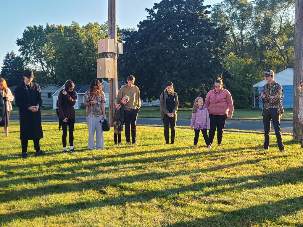 students and parents gathered around a flagpole for a time of prayer