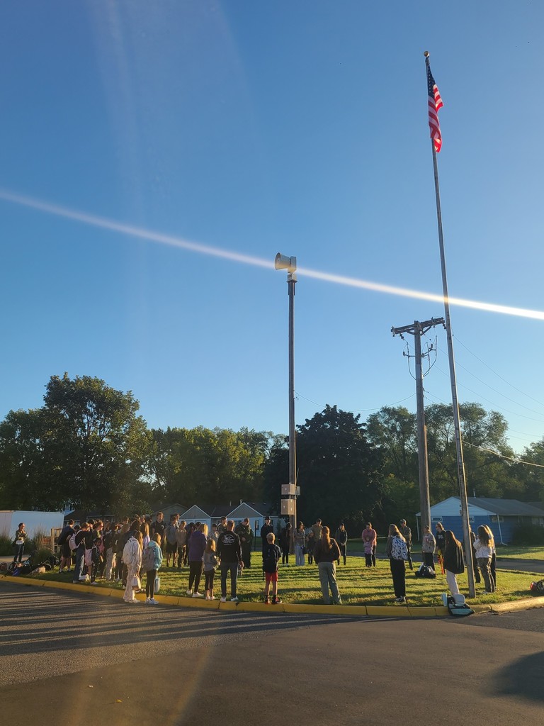 students and parents gathered around a flagpole for a time of prayer