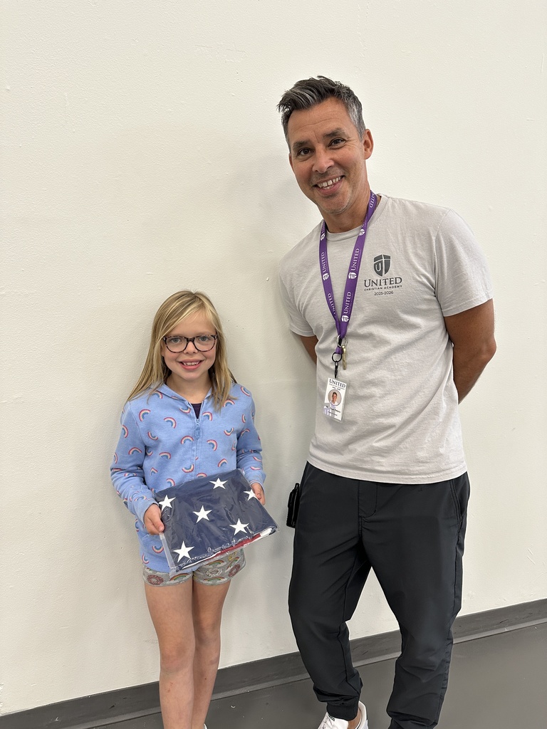 head of school standing next to a student holding an american flag