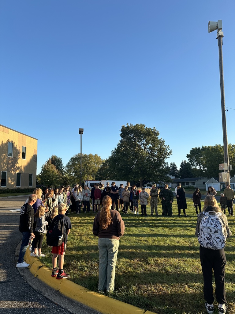 students and parents gathered around a flagpole for a time of prayer