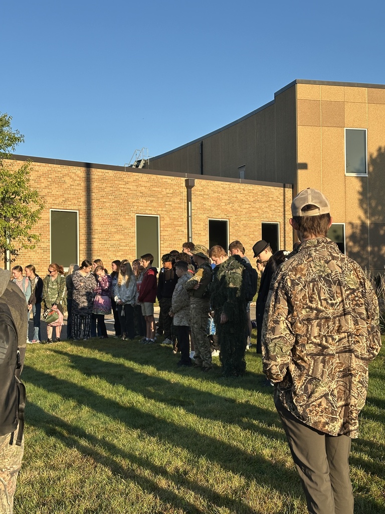 students and parents gathered around a flagpole for a time of prayer