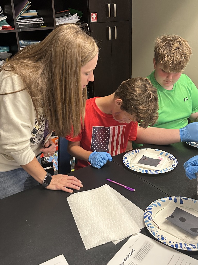 5th grade students looking at a worm on a paper plate