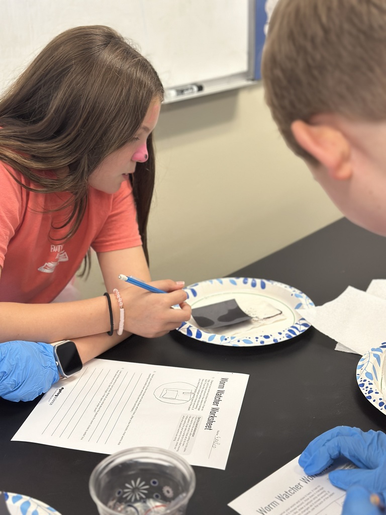 5th grade students looking at a worm on a paper plate