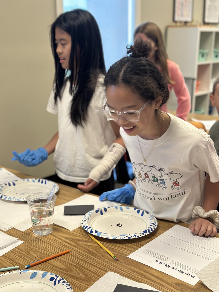 5th grade students looking at a worm on a paper plate