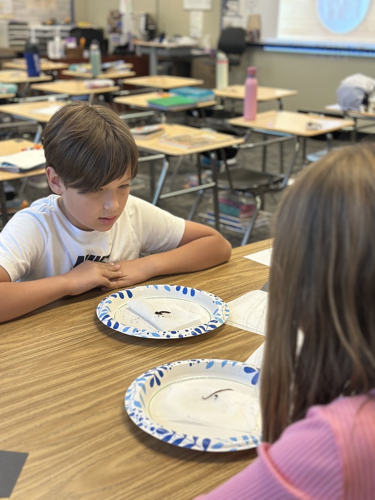 5th grade students looking at a worm on a paper plate