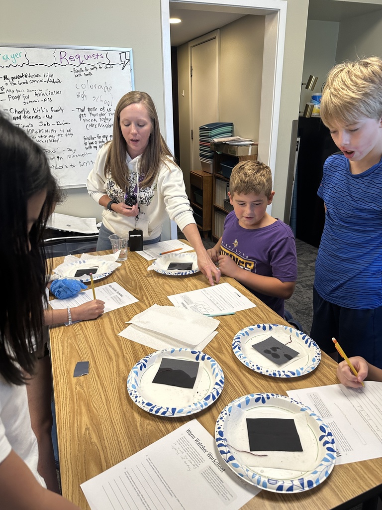 5th grade students looking at a worm on a paper plate