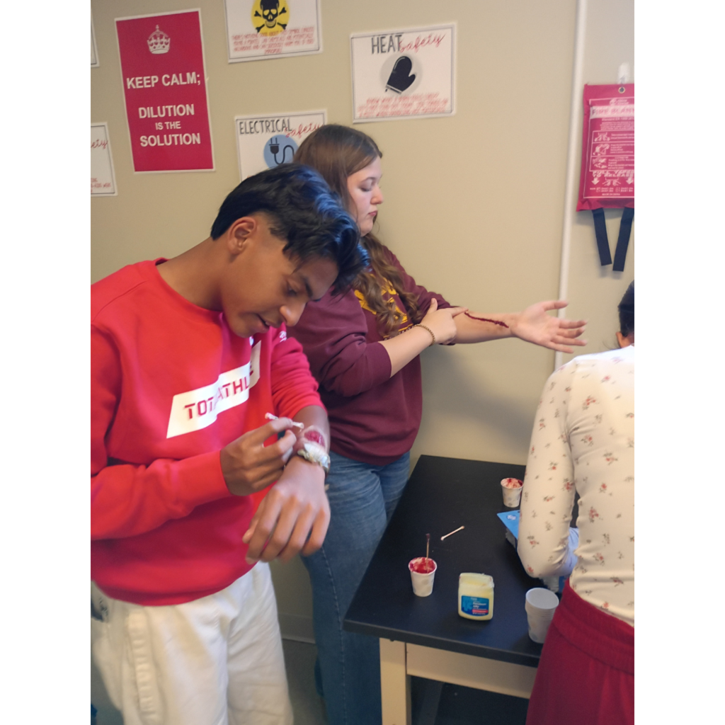 students applying make-up to look like and injury