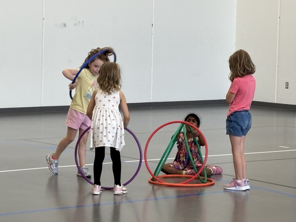 kindergarten students playing a game in PE class involving hula hoops and dodgeballs