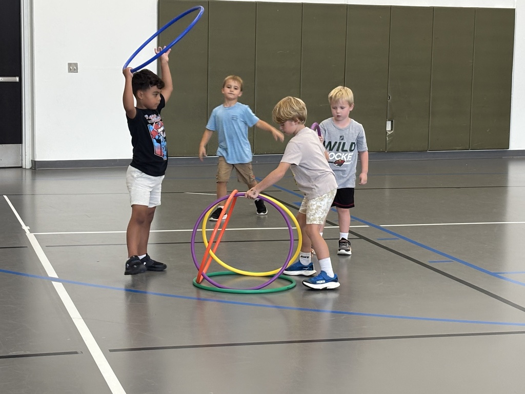 kindergarten students playing a game in PE class involving hula hoops and dodgeballs