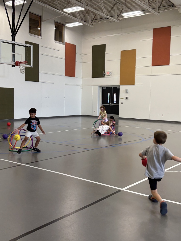 kindergarten students playing a game in PE class involving hula hoops and dodgeballs