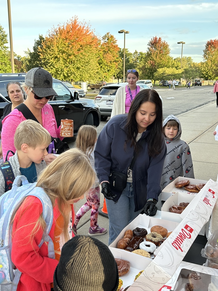 woman helping to hand out donuts to students