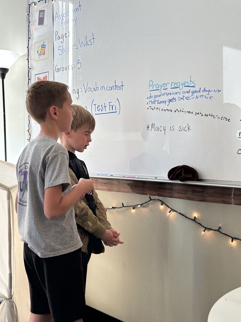 two students looking at prayer requests written on the white board and praying for them