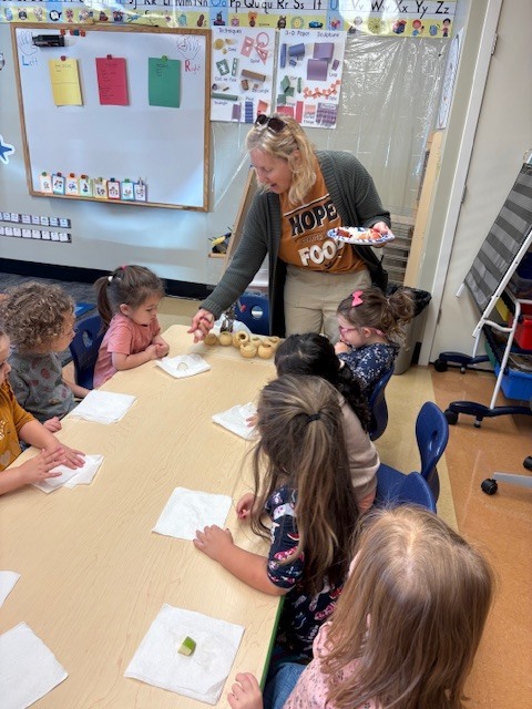 teacher passing out apples to her PreK students