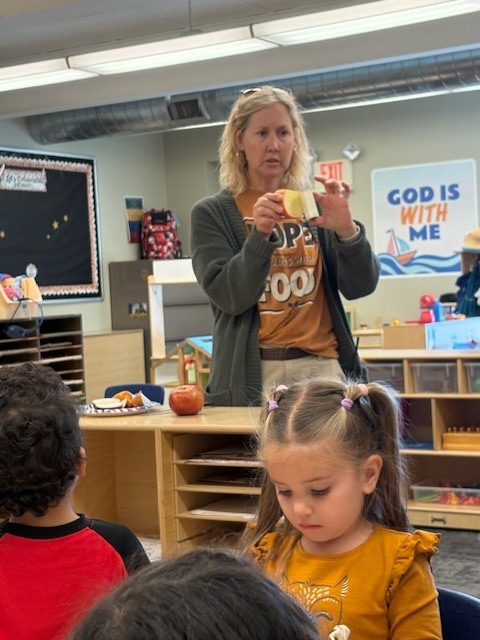 teacher showing an apple to her PreK students