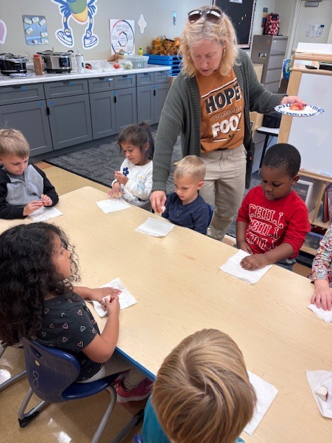 teacher passing out apples to her PreK students