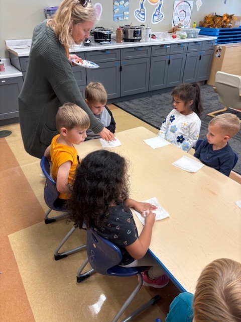 teacher passing out apples to her PreK students