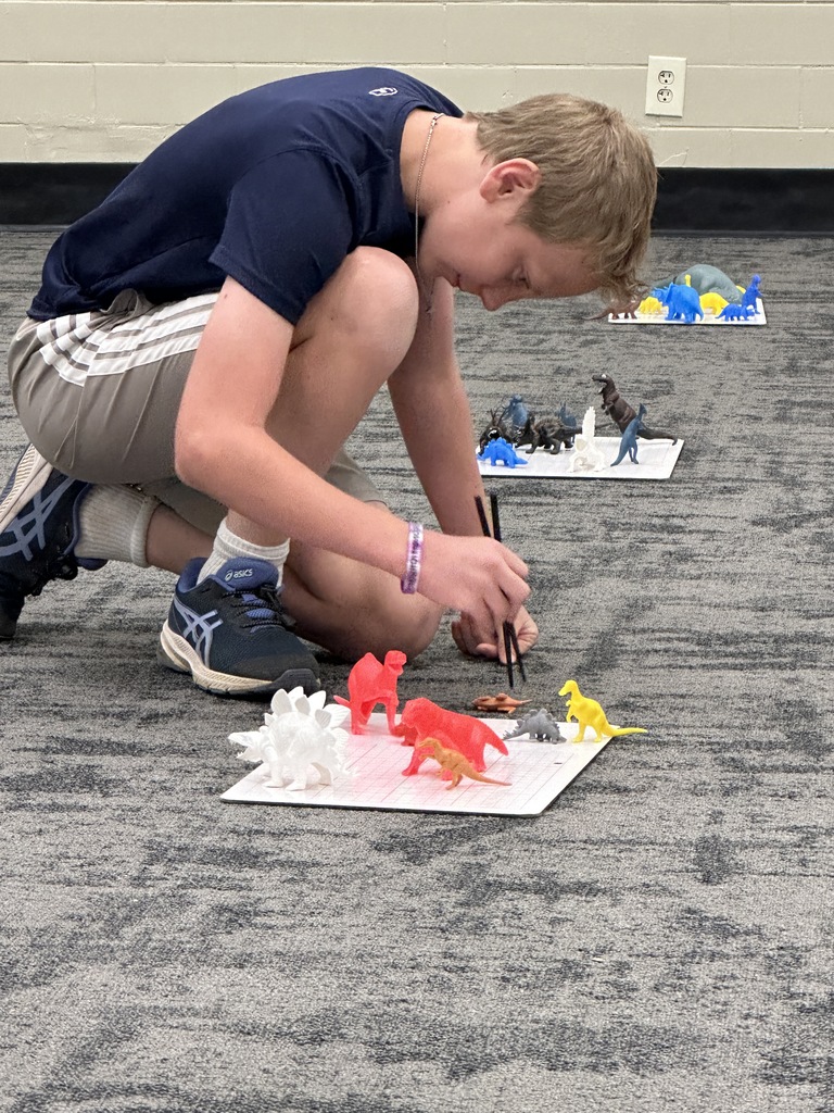 7th grade students participating in a relay race, trying to pick up a toy dinosaur with chopsticks