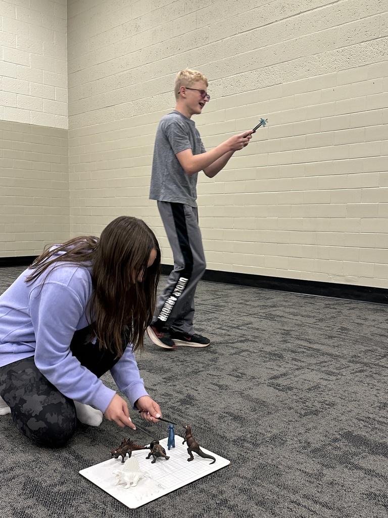 7th grade students participating in a relay race, trying to pick up a toy dinosaur with chopsticks