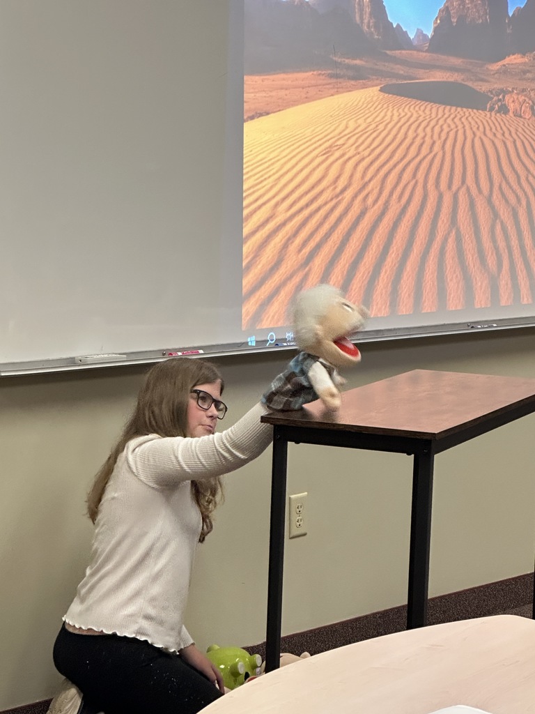 student performing a puppet show as a presentation for her classmates
