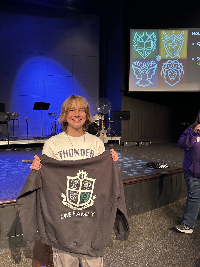 middle school student holding up a sweatshirt that she was given after earning "Student of the Quarter"