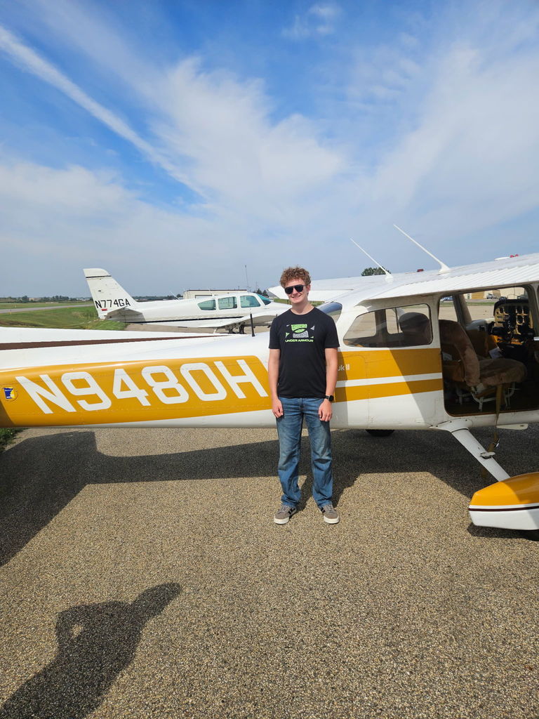 student standing next to a small airplane
