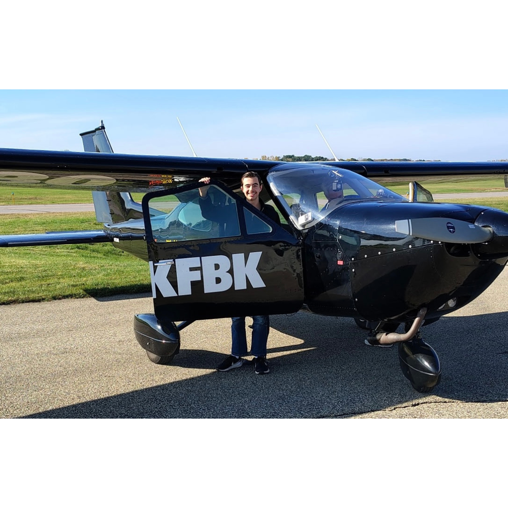 student standing next to a small airplane