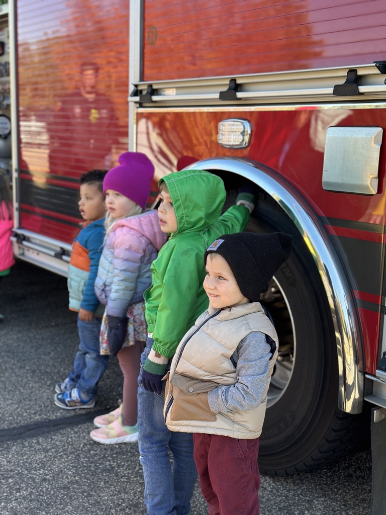 students standing next to the wheel of a firetruck